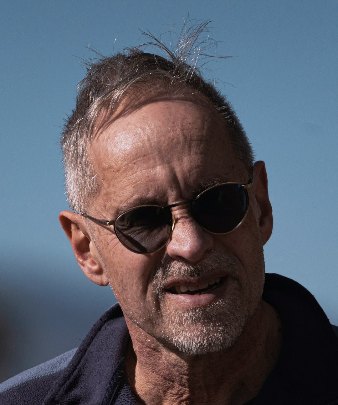 Professional headshot of an older man with glasses